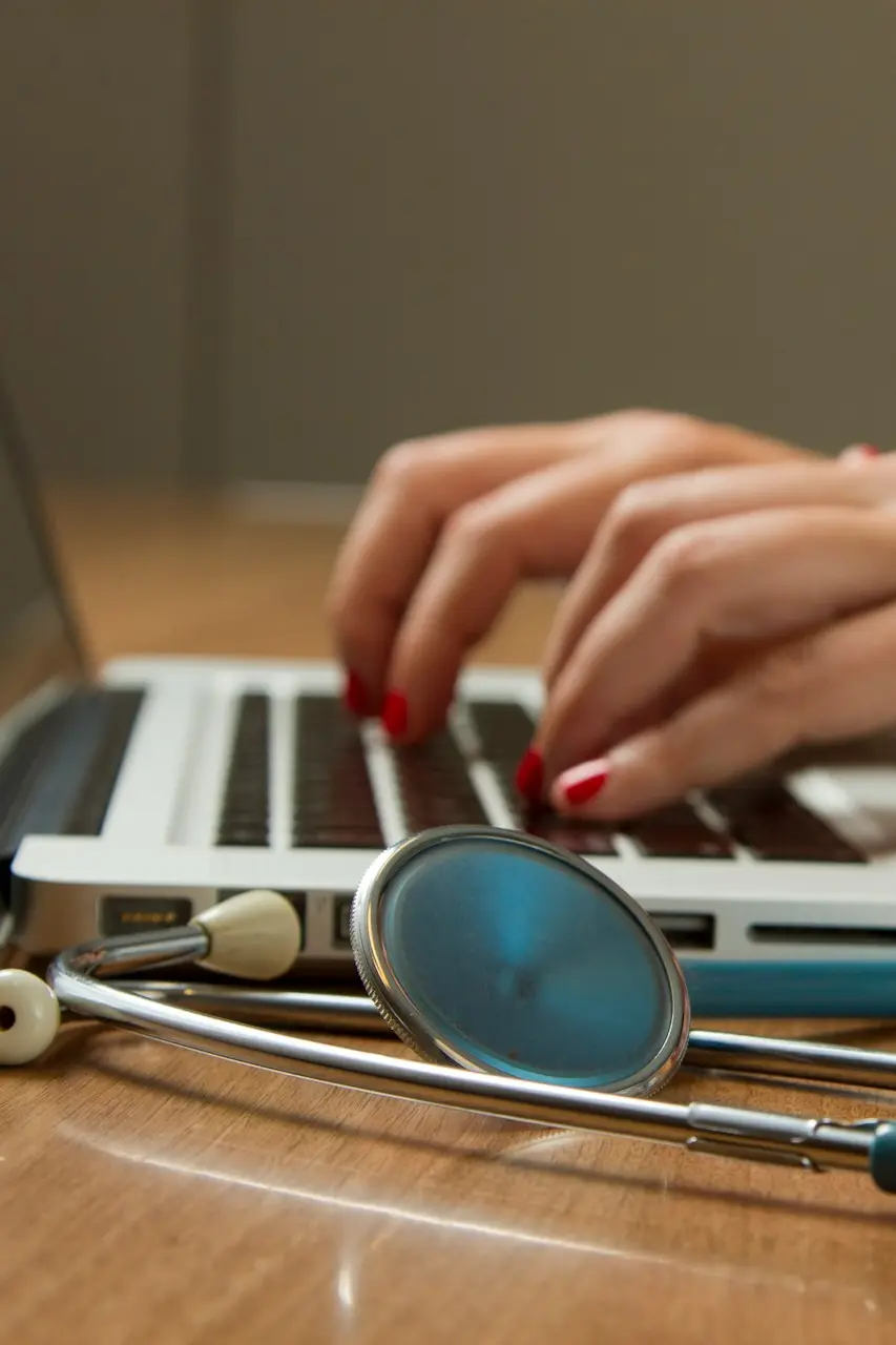 person sitting while using laptop computer and green stethoscope near